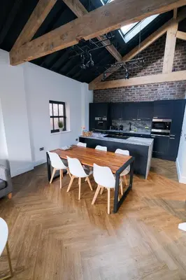 a dining room with a wooden table and white chairs at The Eden Warehouse - Green Apartment, sleeps 5 in Southport