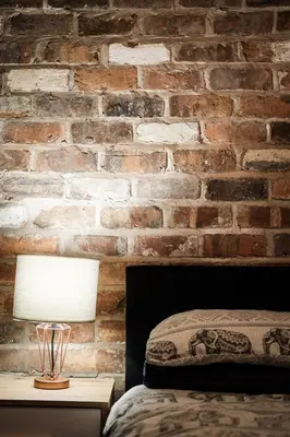 a bedroom with a brick wall and a table with a lamp at The Eden Warehouse - Green Apartment, sleeps 5 in Southport