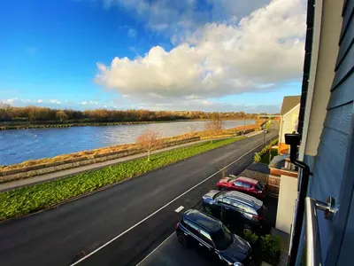 a view of cars parked on a road next to a river at Large En-Suite with Stunning River Views in Lancaster in Torrisholme