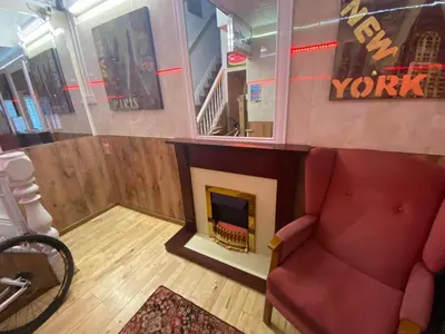 a living room with a fireplace and a red chair at Mellory hotel in Blackpool