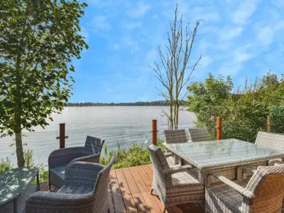 a table and chairs on a deck with a view of the water at Gerrida Lodge in Carnforth