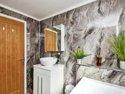 a bathroom with a white sink and a marble wall at Gerrida Lodge in Carnforth
