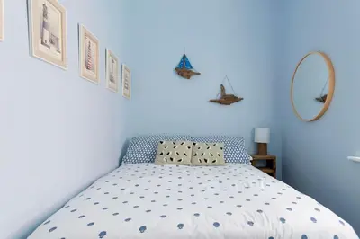 a blue bedroom with a bed and a mirror at Beach Retreat in Lytham St Annes