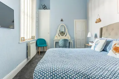 a blue bedroom with a bed and a mirror at Beach Retreat in Lytham St Annes