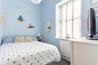 a blue bedroom with a bed and a television at Beach Retreat in Lytham St Annes