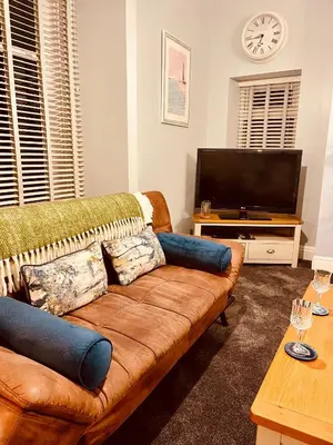 a living room with a brown couch and a flat screen tv at Beach Retreat in Lytham St Annes