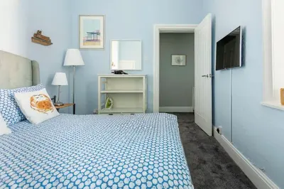 a blue bedroom with a bed and a television at Beach Retreat in Lytham St Annes