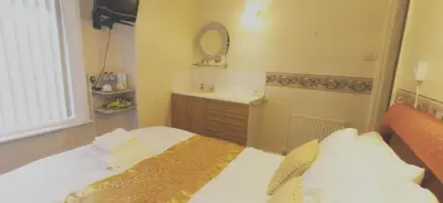 a small bedroom with a bed and a sink at Lily Hotel in Blackpool