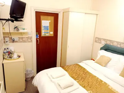 a small room with a bed and a red door at Lily Hotel in Blackpool