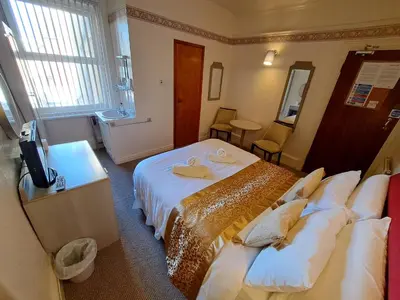 a hotel room with two beds and a television at Lily Hotel in Blackpool