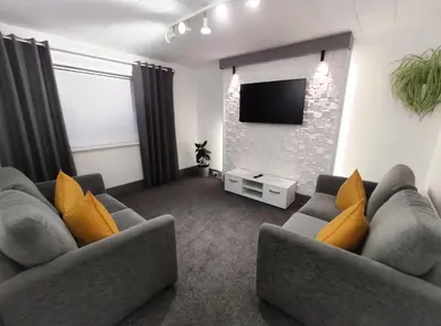 a living room with two couches and a flat screen tv at The Bawdens Holiday Apartments in Blackpool
