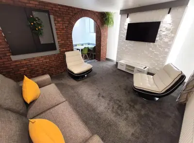 a living room with a couch and chairs and a tv at The Bawdens Holiday Apartments in Blackpool