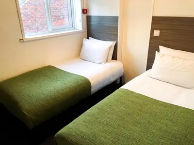 a hotel room with two beds and a window at The Bawdens Holiday Apartments in Blackpool