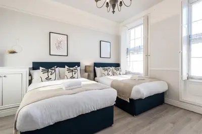 two beds in a bedroom with white walls and windows at Host & Stay - The Seel Street Townhouse in Liverpool