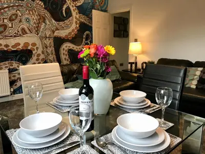 a table with a bottle of wine and plates and glasses at Stylish 3 bedroom house only 5 mins from M6/M58 in Wigan