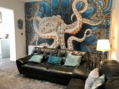 a black leather couch in front of a wall with an octopus at Stylish 3 bedroom house only 5 mins from M6/M58 in Wigan
