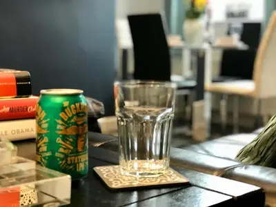 a glass on a coaster next to a can on a table at Stylish 3 bedroom house only 5 mins from M6/M58 in Wigan