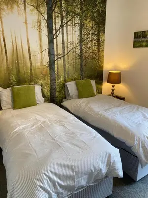 two beds in a room with a painting of trees at Stylish 3 bedroom house only 5 mins from M6/M58 in Wigan
