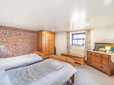 a bedroom with two beds and a brick wall at The Barn in Poulton le Fylde