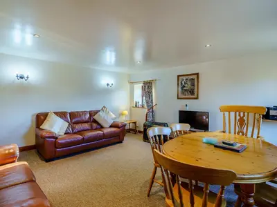 a living room with a table and a couch and a table and chairs at The Shippon in Poulton le Fylde