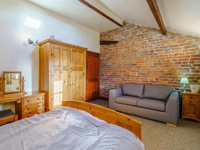 a bedroom with a bed and a couch and a brick wall at The Shippon in Poulton le Fylde