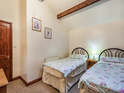 a bedroom with two beds and a table at The Hay Loft in Poulton le Fylde