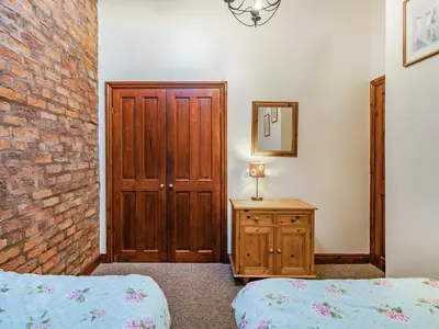 a bedroom with two beds and a brick wall at The Hay Loft in Poulton le Fylde