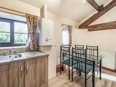 a kitchen with a sink and a table with two chairs at The Hay Loft in Poulton le Fylde