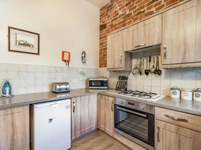 a kitchen with wooden cabinets and a brick wall at The Hay Loft in Poulton le Fylde
