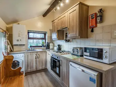 a kitchen with wooden cabinets and white appliances at The Granary in Poulton le Fylde