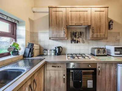 a kitchen with wooden cabinets and a stove top oven at The Granary in Poulton le Fylde