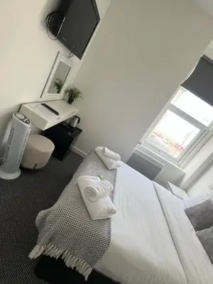 a bedroom with a bed and a desk and a window at Alexandra Hotel in Blackpool