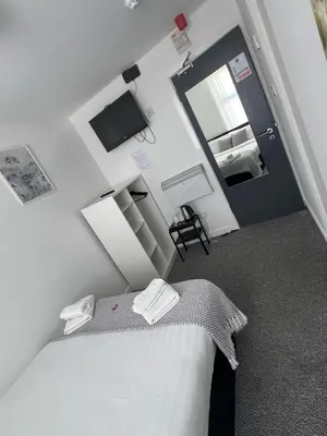 a white bedroom with a bed and a mirror at Alexandra Hotel in Blackpool