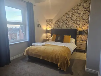 a bedroom with a large bed and a window at Avondale,2 bed lakeside on the Promenade, free parking & wifi in Southport