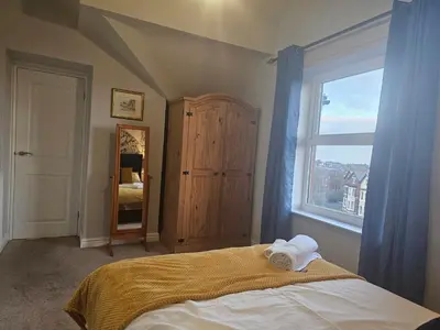 a bedroom with a bed and a large window at Avondale,2 bed lakeside on the Promenade, free parking & wifi in Southport