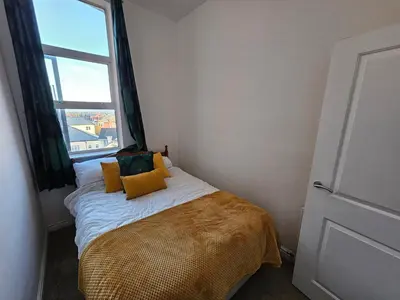 a small bedroom with a bed with a window at Avondale,2 bed lakeside on the Promenade, free parking & wifi in Southport