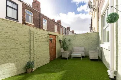 a patio with chairs and a table and a brick wall at Arkles House - Air Host & Stay - Anfield in Liverpool