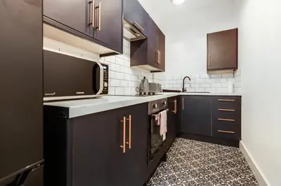 a kitchen with black cabinets and a microwave at Queen Street Apartments by Sasco in Blackpool