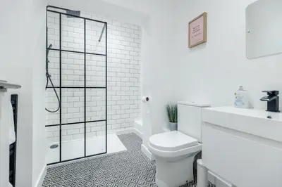 a white bathroom with a shower and a toilet at Queen Street Apartments by Sasco in Blackpool