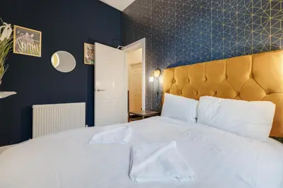 a bedroom with a white bed with a blue wall at Queen Street Apartments by Sasco in Blackpool