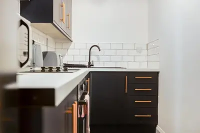 a kitchen with black cabinets and a sink at Queen Street Apartments by Sasco in Blackpool