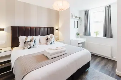 a bedroom with a large bed with a wooden headboard at Prime Suites Lytham in Lytham St Annes