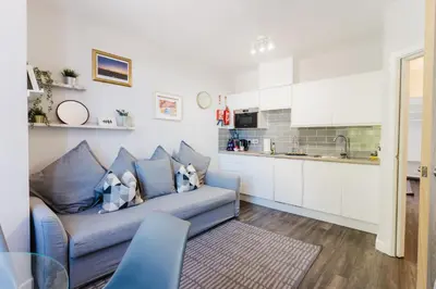 a living room with a couch and a kitchen at Prime Suites Lytham in Lytham St Annes