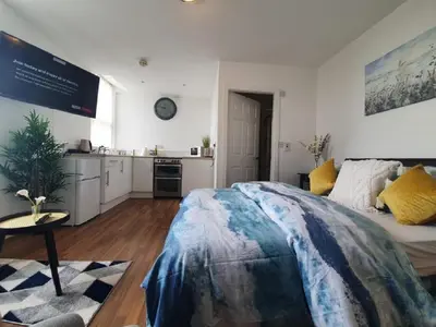 a bedroom with a large bed and a kitchen at CityNights Studios with Free Parking in Liverpool