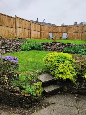 a backyard with a fence and a garden with flowers at Gorgeous Cottage near Cartmel with FREE SPA Access in Holker