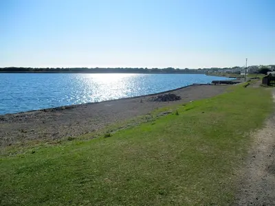 a beach with a path next to a body of water at Plot 8 Lakeside Cabin, Wyldecrest, Millom in Millom