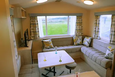 a living room with a couch and a table at Plot 8 Lakeside Cabin, Wyldecrest, Millom in Millom