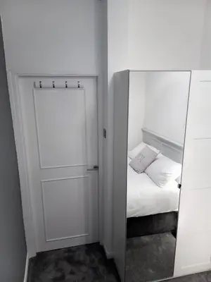 a small bedroom with a mirror and a bed at St Annes Lodge Apartments, Lytham St Annes in Lytham St Annes