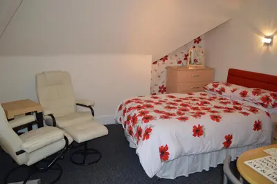 a bedroom with a bed and two chairs in it at Ayrton House Holiday Apartments in Blackpool