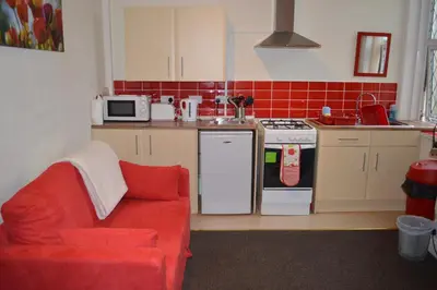 a kitchen with a red couch and a kitchen with a stove at Ayrton House Holiday Apartments in Blackpool